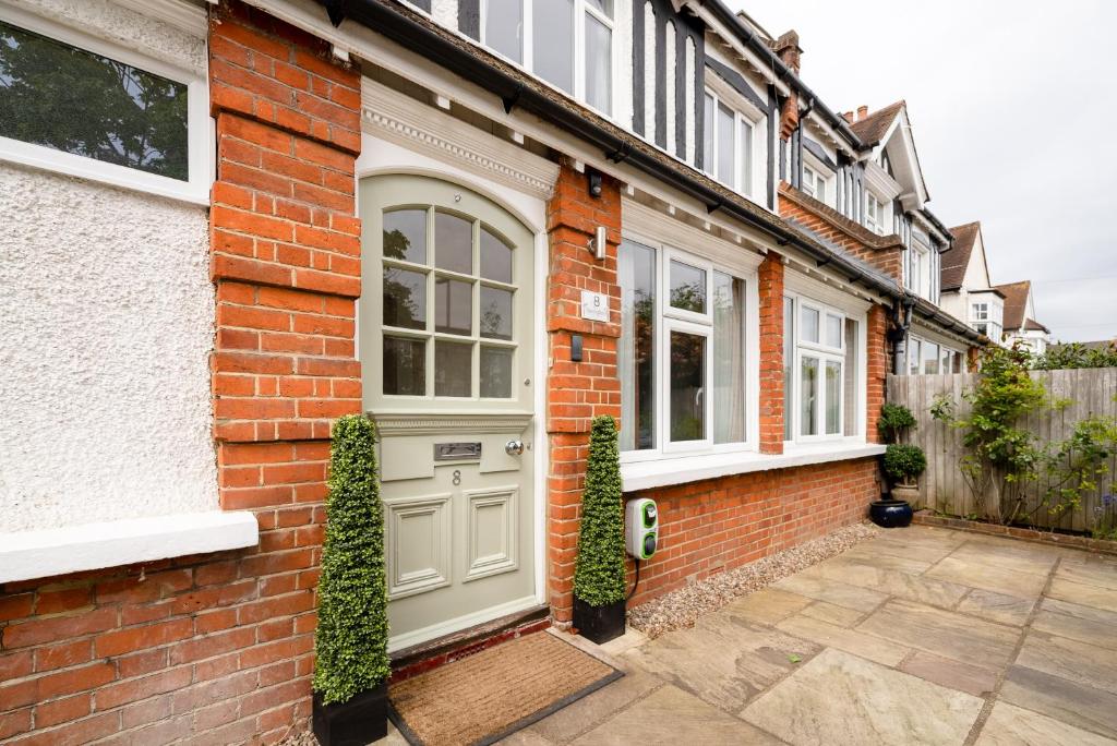 a brick house with a grey door and windows at Luxury three bedroom serviced apartment - Springfield in Claygate