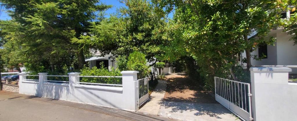 a white fence in front of a house with trees at Residence Paula in Jadranovo