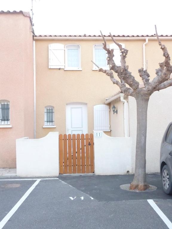 une maison avec une clôture et un arbre dans un parking dans l'établissement Villa St Cécile Vias, à Vias