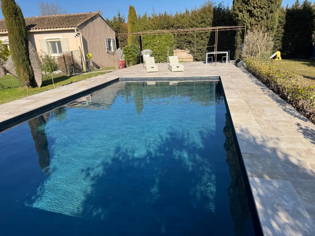 une piscine avec de l'eau bleue dans une cour arrière dans l'établissement Villa d Agathe en Provence Graveson, à Graveson