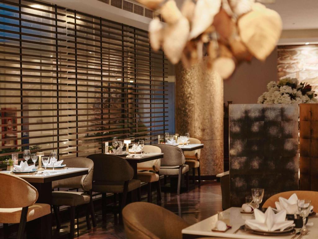 a restaurant with tables and chairs and a large window at Pullman Phuket Karon Beach Resort in Karon Beach