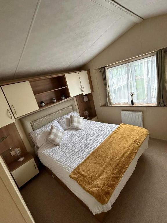 a bedroom with a bed with a yellow blanket on it at Metcalfes family caravan in Heysham