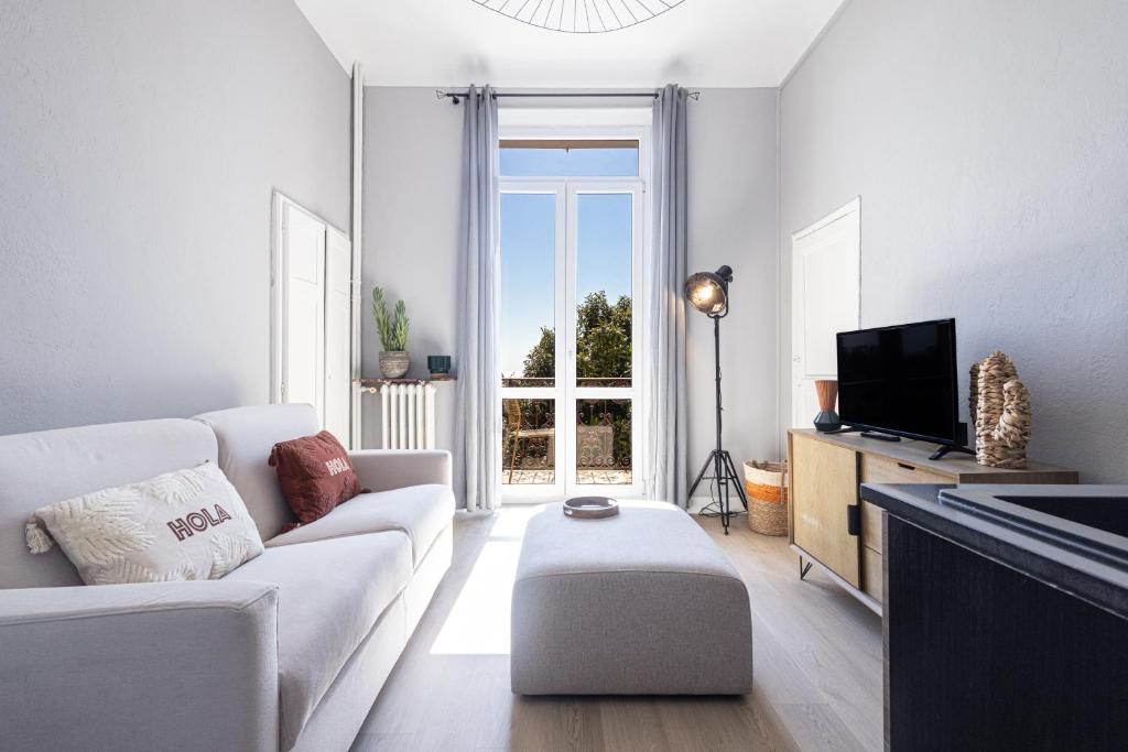 un salon avec un canapé blanc et une télévision dans l'établissement Coquette studette, aperçu mer, à 400m des plages, à Villeneuve-Loubet