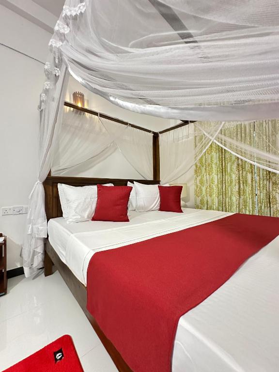 a bedroom with two beds with red sheets and a canopy at Seagate Villa in Bentota