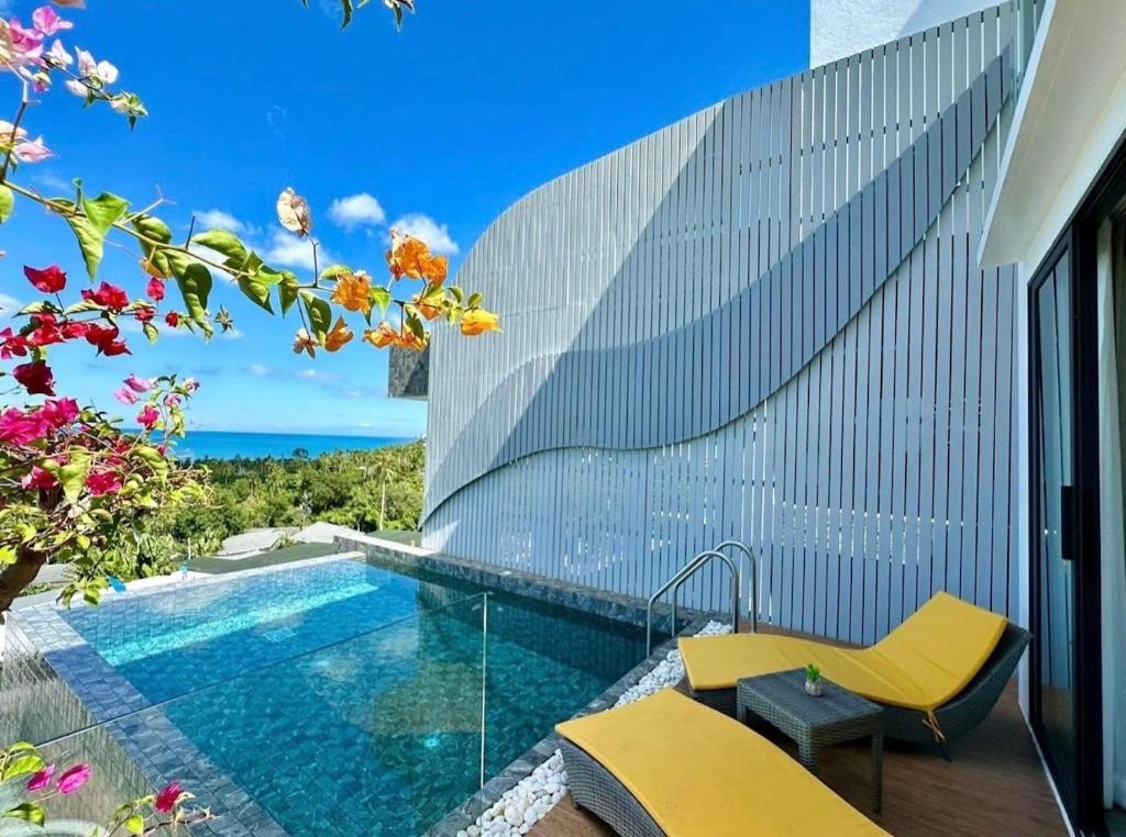 een zwembad met gele stoelen naast een gebouw bij The Blue Lion Villa Samui in Chaweng Noi Beach