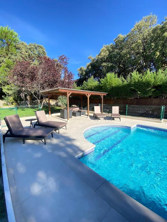 a swimming pool with two chairs and a gazebo at Quinta El Escorial in El Escorial