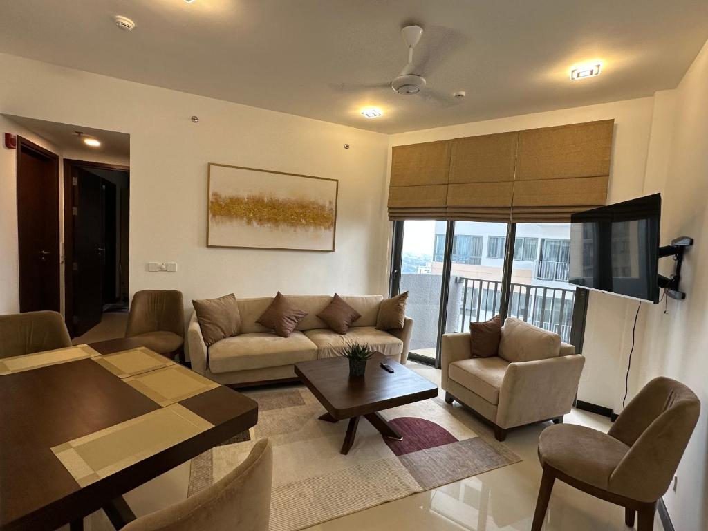 ein Wohnzimmer mit einem Sofa, Stühlen und einem TV in der Unterkunft Colombo luxury two bedroom Apartments Trizen in Colombo
