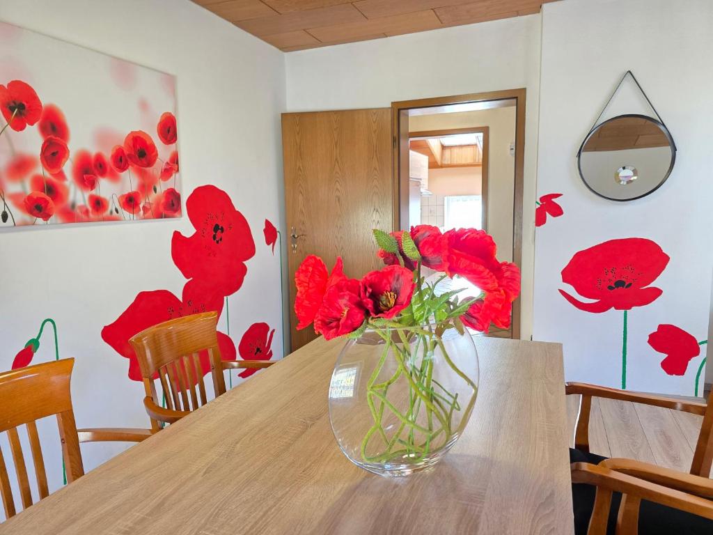 un jarrón lleno de flores rojas sentado en una mesa en ELENA flat Mohn Duisburg Zentrum, en Duisburg