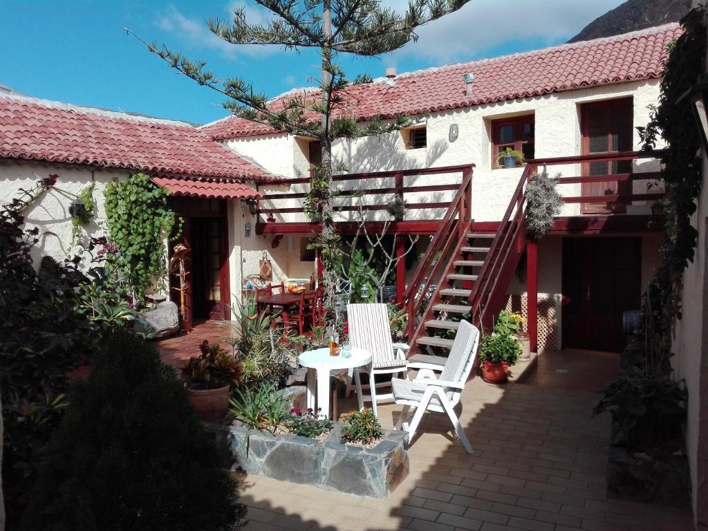 una casa con 2 sillas blancas y una mesa en el patio en Finca Patio Canario, en Arona