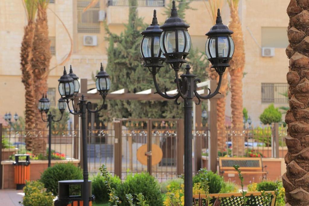 une rangée de lampadaires dans un parc avec des palmiers dans l'établissement Montana Residence, à Amman