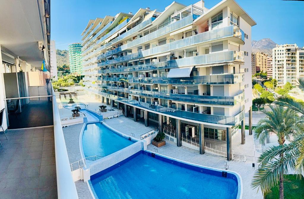 an apartment building with a swimming pool in front of it at Apartamento Elegance La Cala Benidorm in Benidorm