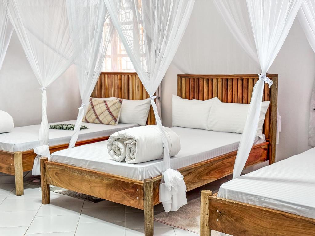 two beds in a room with mosquito nets at Karibu Africa Home in Moshi