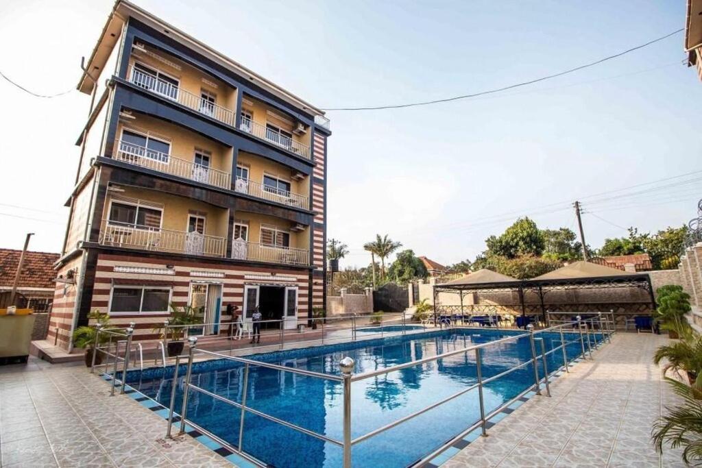 un hôtel avec une piscine devant un bâtiment dans l'établissement Inophine Boutique Hotel Entebbe, à Entebbe