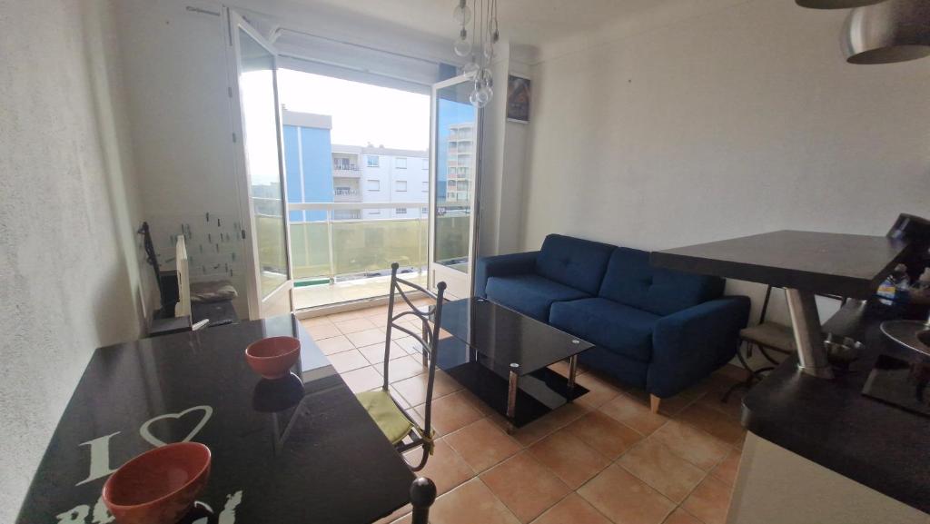 un salon avec un canapé bleu et une table dans l'établissement Au Petit Miramar - Joli T2 face à la mer avec parking, à Saint Cyprien Plage