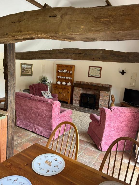a living room with pink furniture and a fireplace at Captains Cottage Dover in Wootton