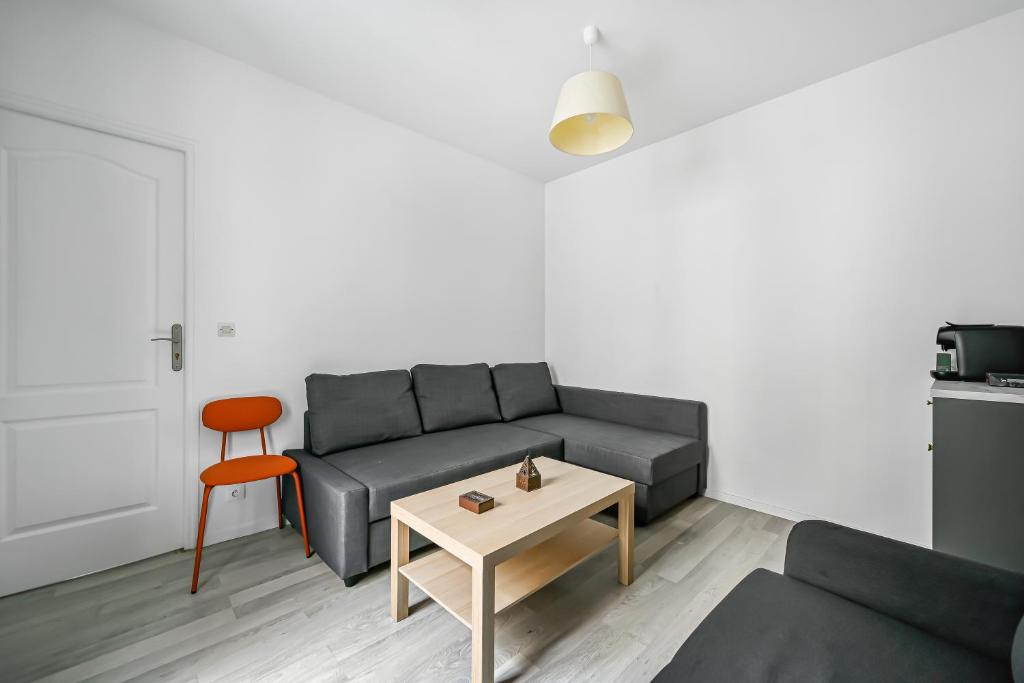 un salon avec un canapé et une table dans l'établissement L'Atelier Secret - Batignolles - Métro - Paris 17, à Paris