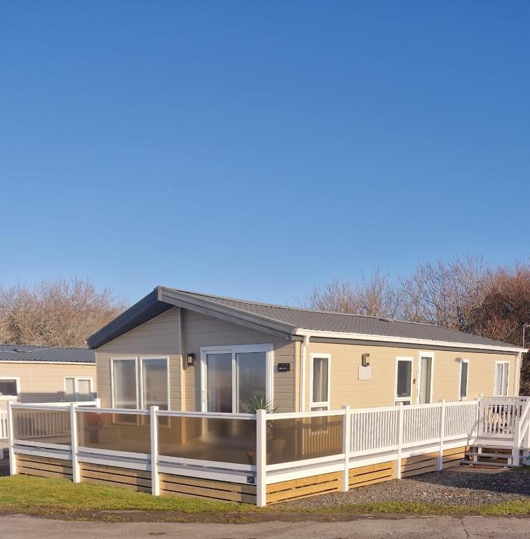 a mobile home with a white fence at Coastal Retreat Lodge in Morecambe