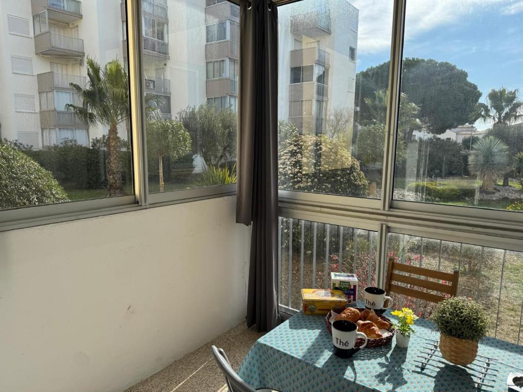 - une table dans une chambre avec vue sur un balcon dans l'établissement Sol-y-Days Goelette, Agréable appartement en RDC avec parking, proche du centre-ville et de la plage, au Grau-du-Roi