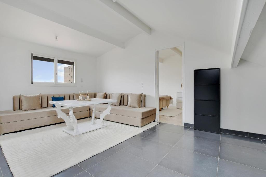 un salon blanc avec une table et un canapé dans l'établissement Le Nova - 2 Prs - Wifi - Proche Paris, à Aubervilliers