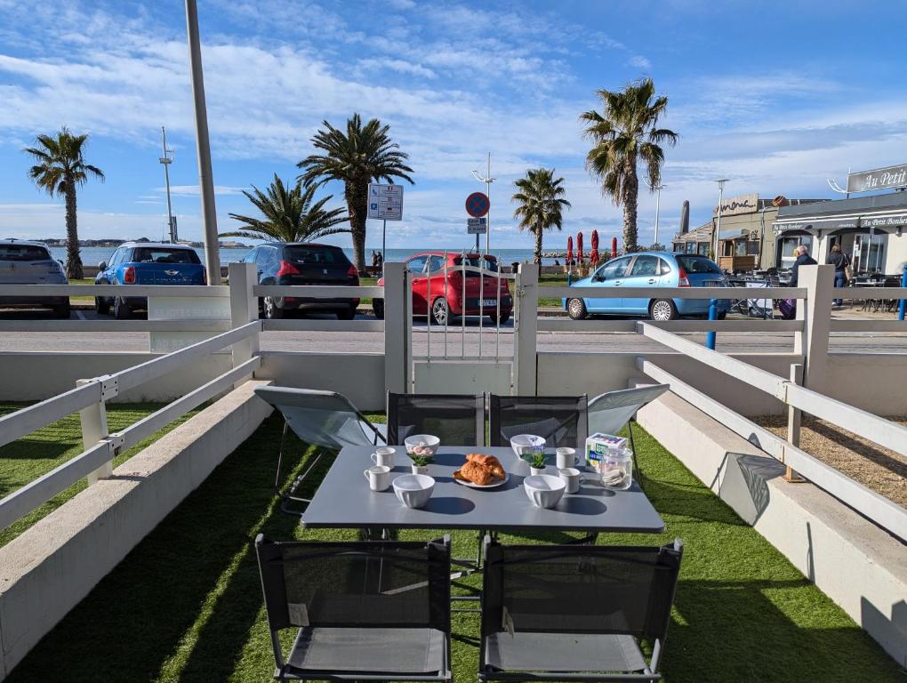 - une table avec une assiette de nourriture sur le balcon dans l'établissement Sol-y-Days Goeland, Appartement avec terrasse front de mer et place de parking en centre-ville, au Grau-du-Roi