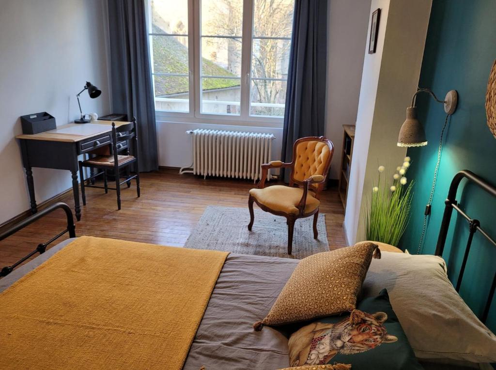 une chambre avec un lit, un bureau et une chaise dans l'établissement L'Amandine, à Saint-Amand-en-Puisaye