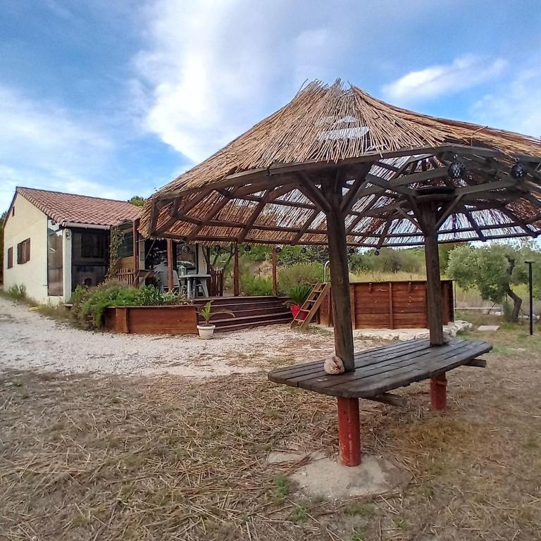un banc avec un parasol en paille devant un bâtiment dans l'établissement La Maisonnette de Saint-Julien, à Martigues