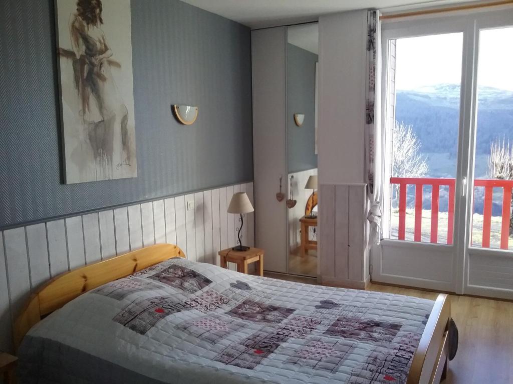a bedroom with a bed and a large window at Auberge du Col de Neronne in Le Falgoux