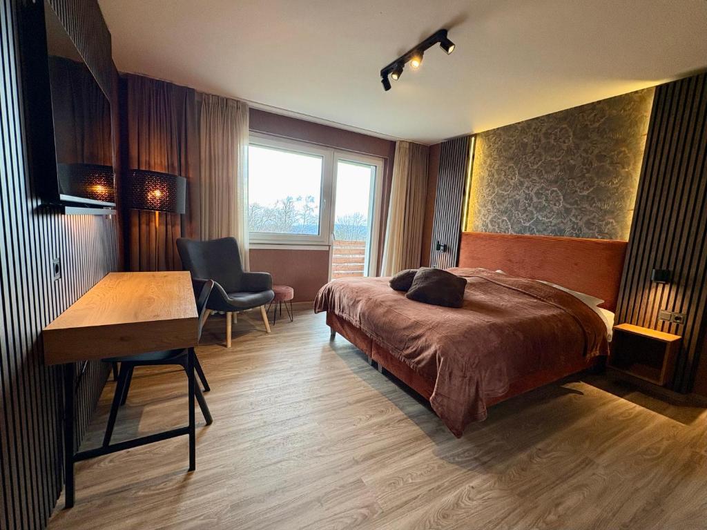 a bedroom with a bed and a desk and a chair at Berghotel Hohegeiß in Hohegeiß