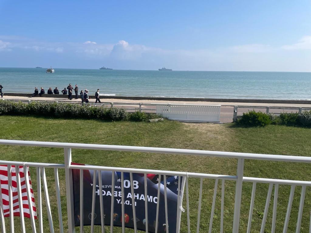 - une vue sur la plage et l'océan depuis une clôture dans l'établissement Maison avec vue mer à Omaha Beach - idéal familles, à Saint-Laurent-sur-Mer