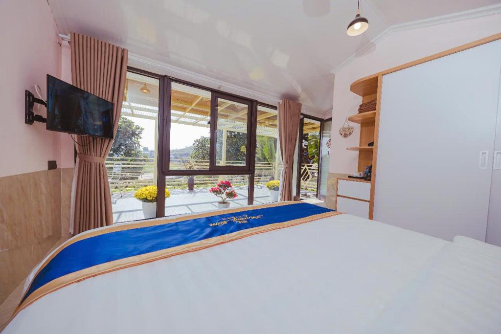 a bedroom with a large bed and a large window at Phương Nam Garden in Ba Vì