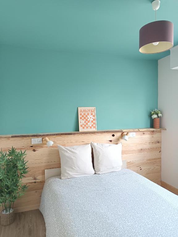 une chambre avec un lit avec un mur bleu dans l'établissement T2 avec Wifi et parking - 700m du centre ville, à Dax