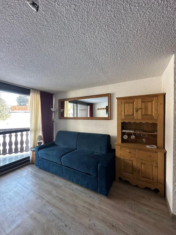 un salon avec un canapé bleu et une fenêtre dans l'établissement Charmant appartement, à Les Deux Alpes