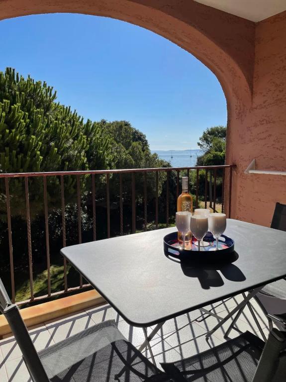 - une table sur un balcon avec des verres et une bouteille de vin dans l'établissement T3 Vue mer les pieds dans l'eau, piscine, clim, à Hyères