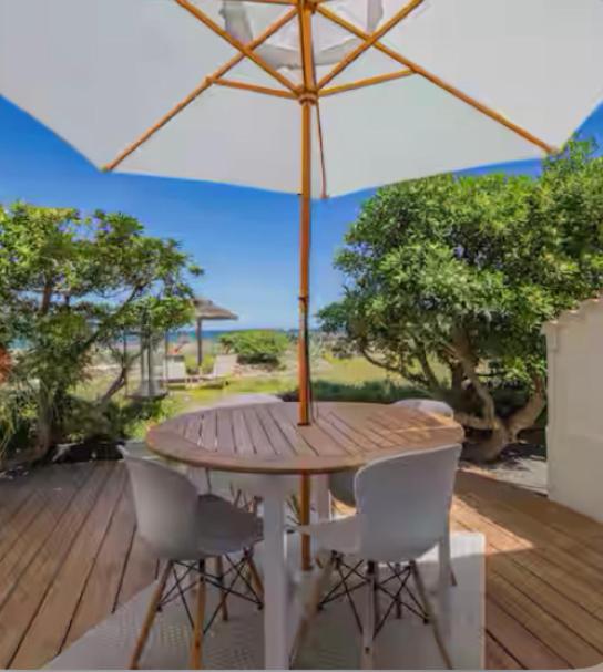 une table en bois avec un parasol sur une terrasse dans l'établissement Bord de mer, superbe studio tout confort, à Hyères