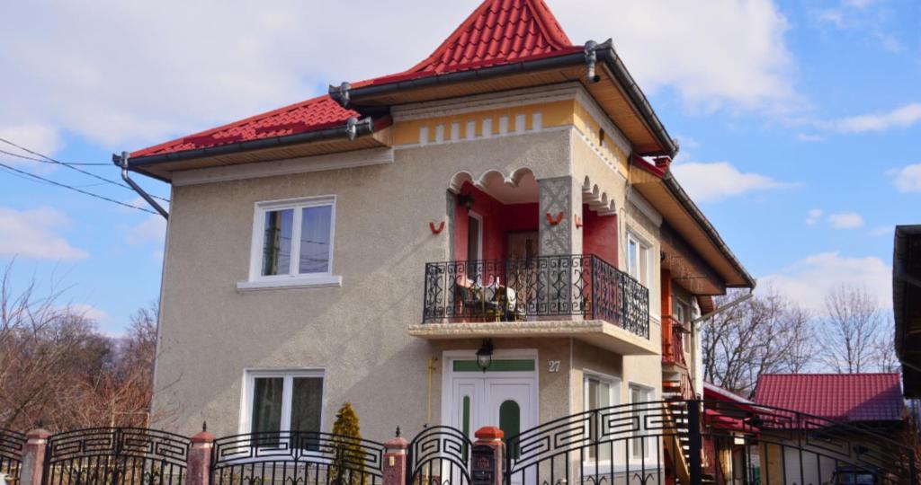 une maison avec un toit rouge et un balcon dans l'établissement Casa Coralis, à Călimăneşti
