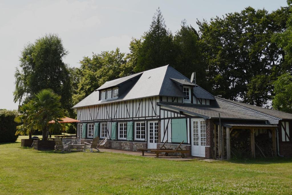 une maison avec un toit en gambrel sur une pelouse dans l'établissement Chaleureux cottage normand en zone Natura 2000, à Freneuse-sur-Risle