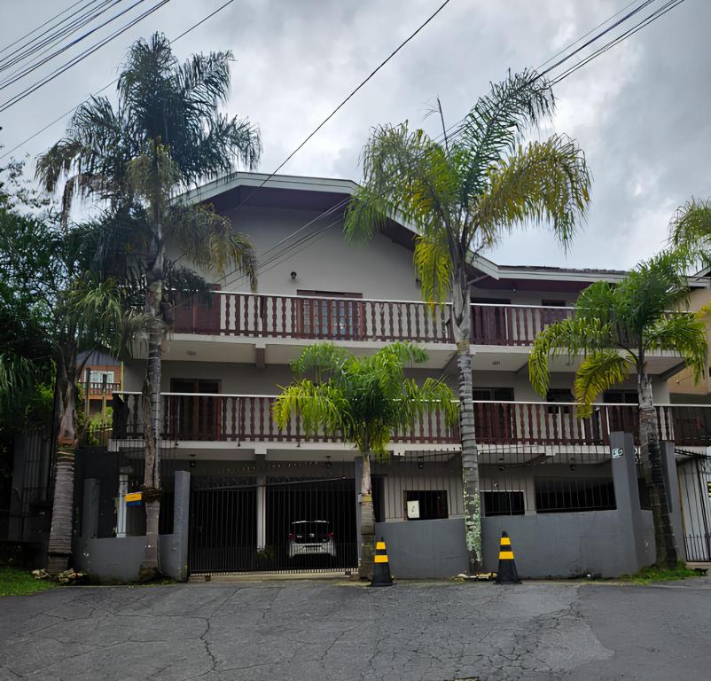 a building with palm trees in front of it at Pousada Portal da Serra in Campos do Jordão