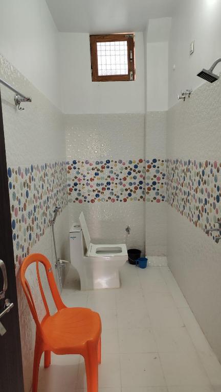 a bathroom with a toilet and a orange chair at Ravi villa in Prayagraj