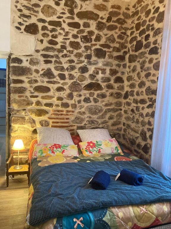 un lit dans une chambre avec un mur en pierre dans l'établissement Appartement entier, terrasse, 4 personnes sur le GR10, à Saint-Étienne-de-Baïgorry