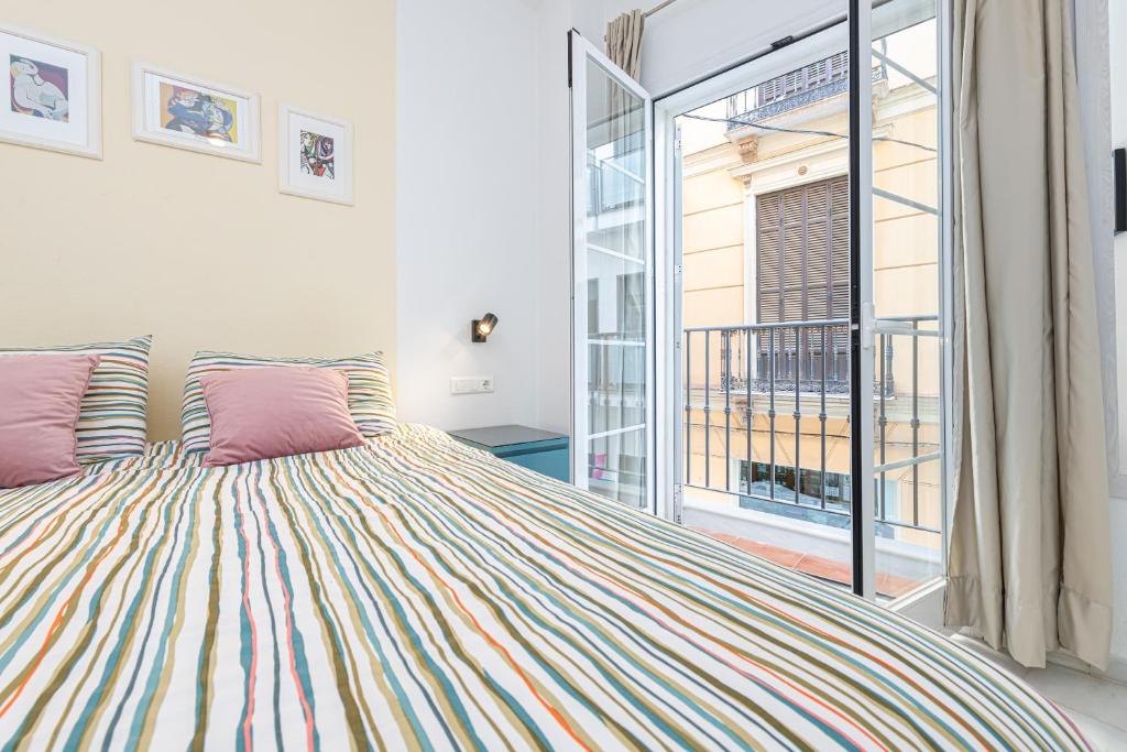 a bedroom with a large bed and a window at Mi Casa es Tu Casa - Malaga Center - Fiber WiFi in Málaga