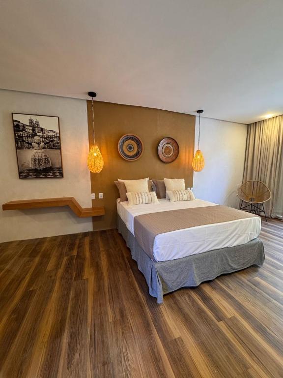 a bedroom with a large bed and wooden floors at Casas Oba in Morro de São Paulo