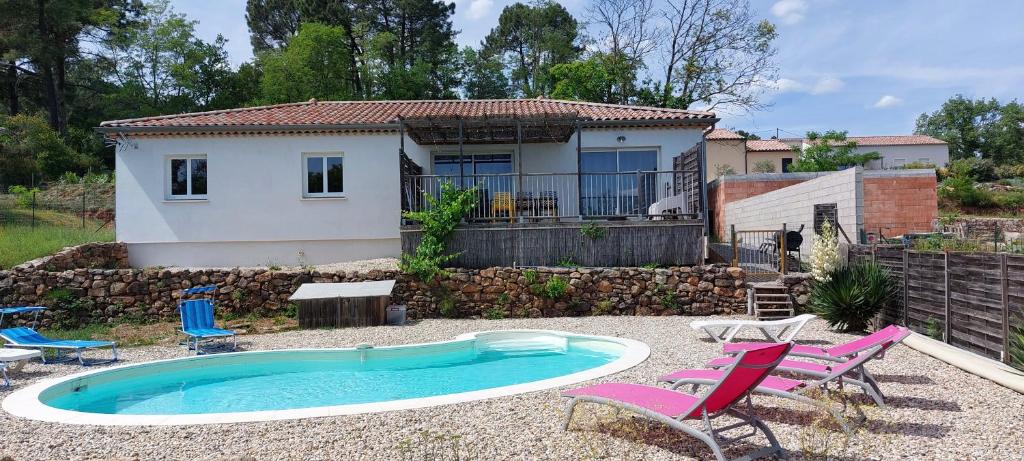 une petite piscine avec des chaises et une maison en arrière-plan dans l'établissement Loumapé, à Joyeuse