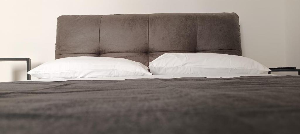 a bed with white pillows and a brown headboard at Alloggio Turistico fata in Civitavecchia