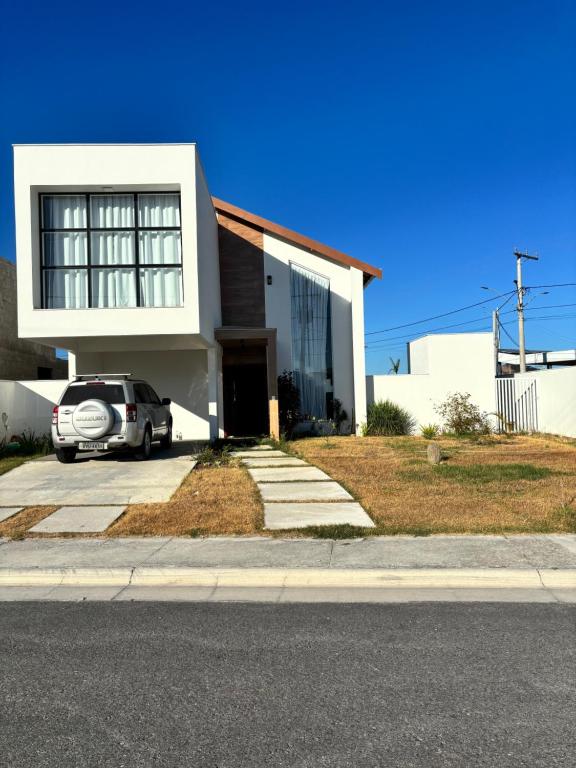 une maison blanche avec une voiture garée devant elle dans l'établissement Casa da Mãe São Pedro, à São Pedro da Aldeia