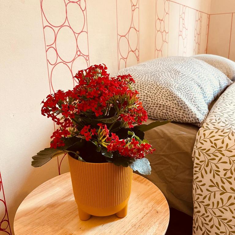 a vase with red flowers on a table next to a bed at La Caravella apartament in Rapallo