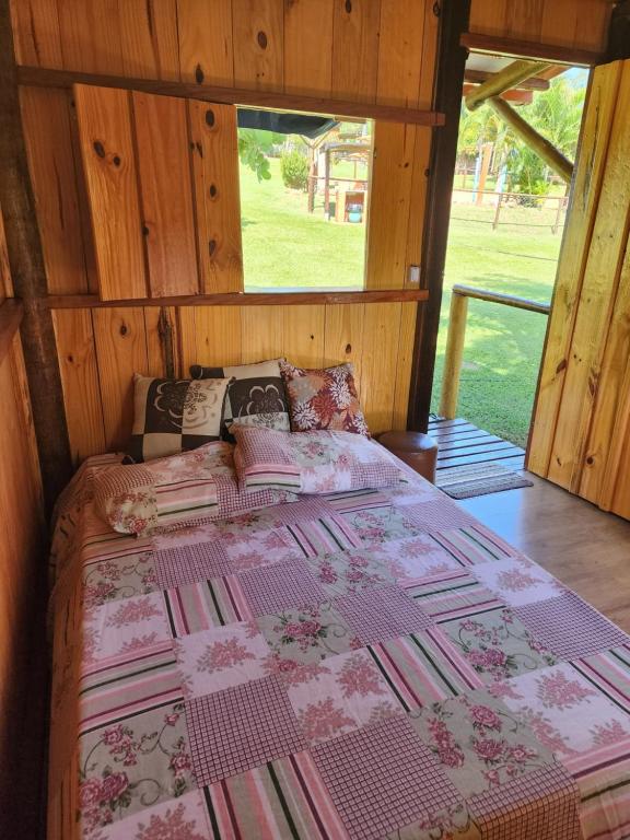 ein Schlafzimmer mit einem Bett mit einer Steppdecke darauf in der Unterkunft Cabana Hostel Eco Park in São Pedro