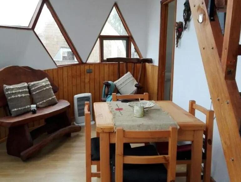 a dining room with a table and a room with windows at Chiloe Domos in Huenao