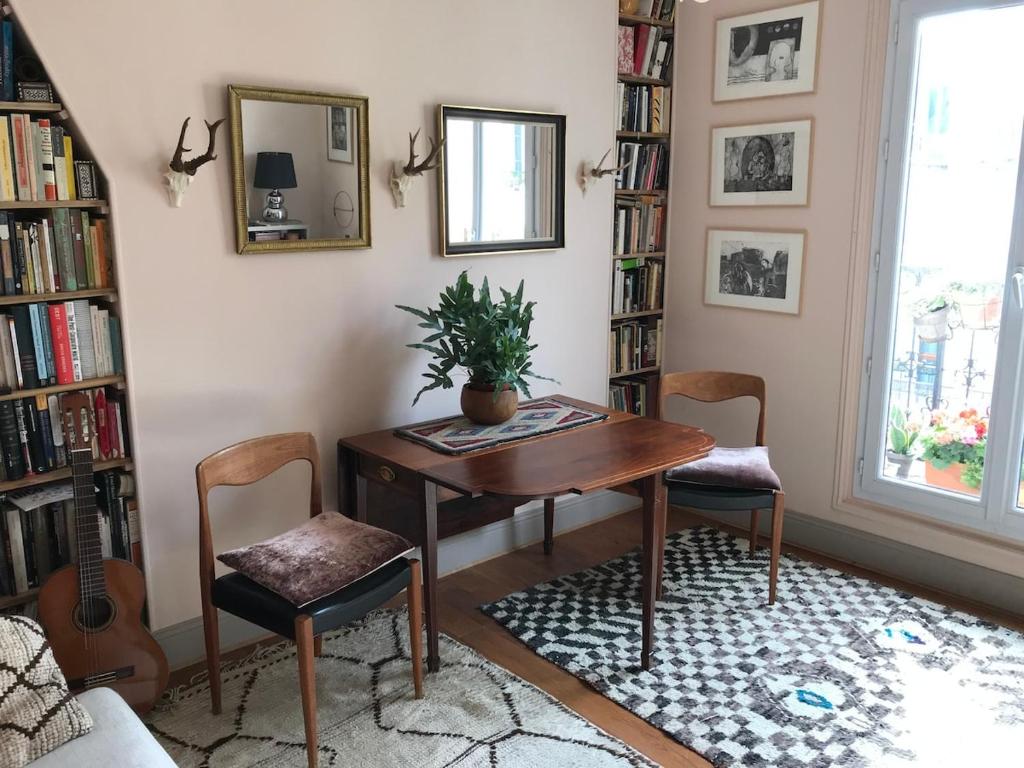 Cette chambre comprend un bureau, des chaises et des étagères. dans l'établissement Cozy Montmartre apartment with views over rooftops, à Paris