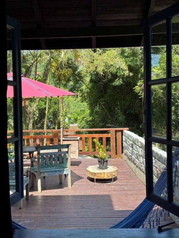 a wooden deck with a bench and a table at Pousada Maikai Garden in Porto Belo