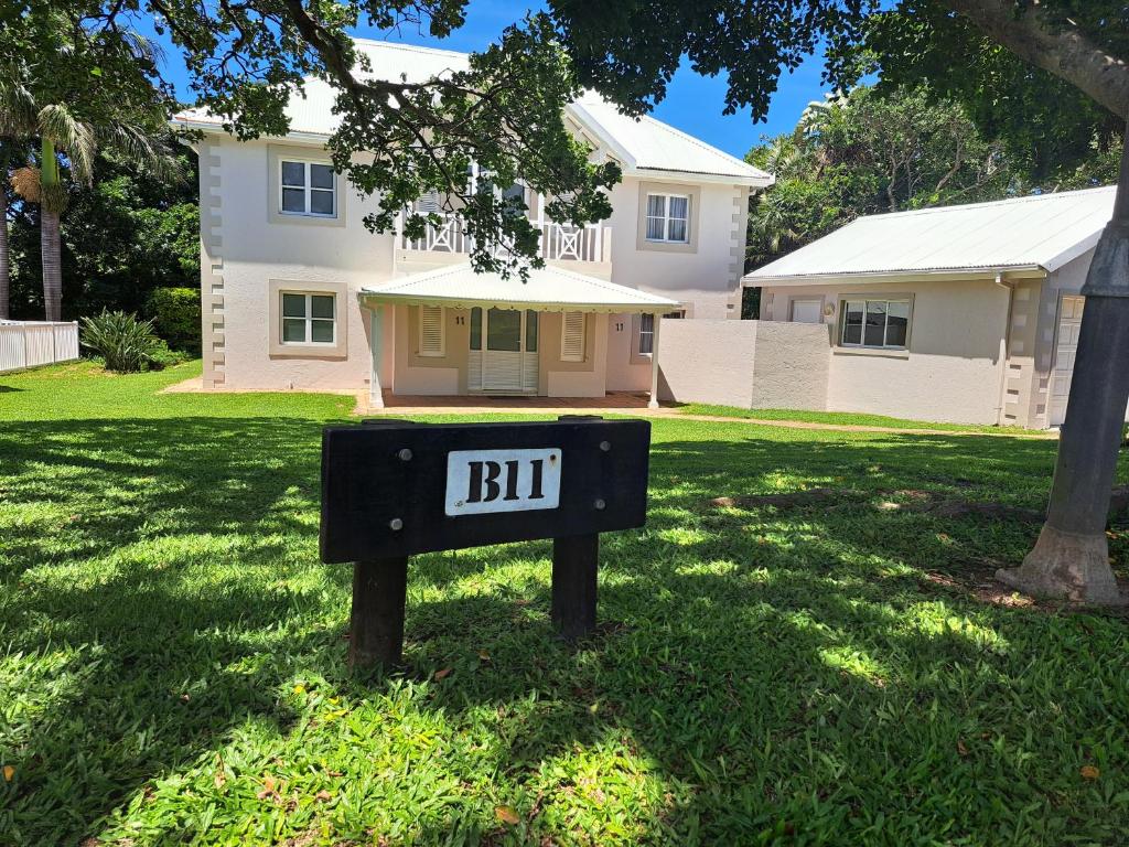 a sign in the grass in front of a house at Caribbean Estate Guest House B11 in Port Edward
